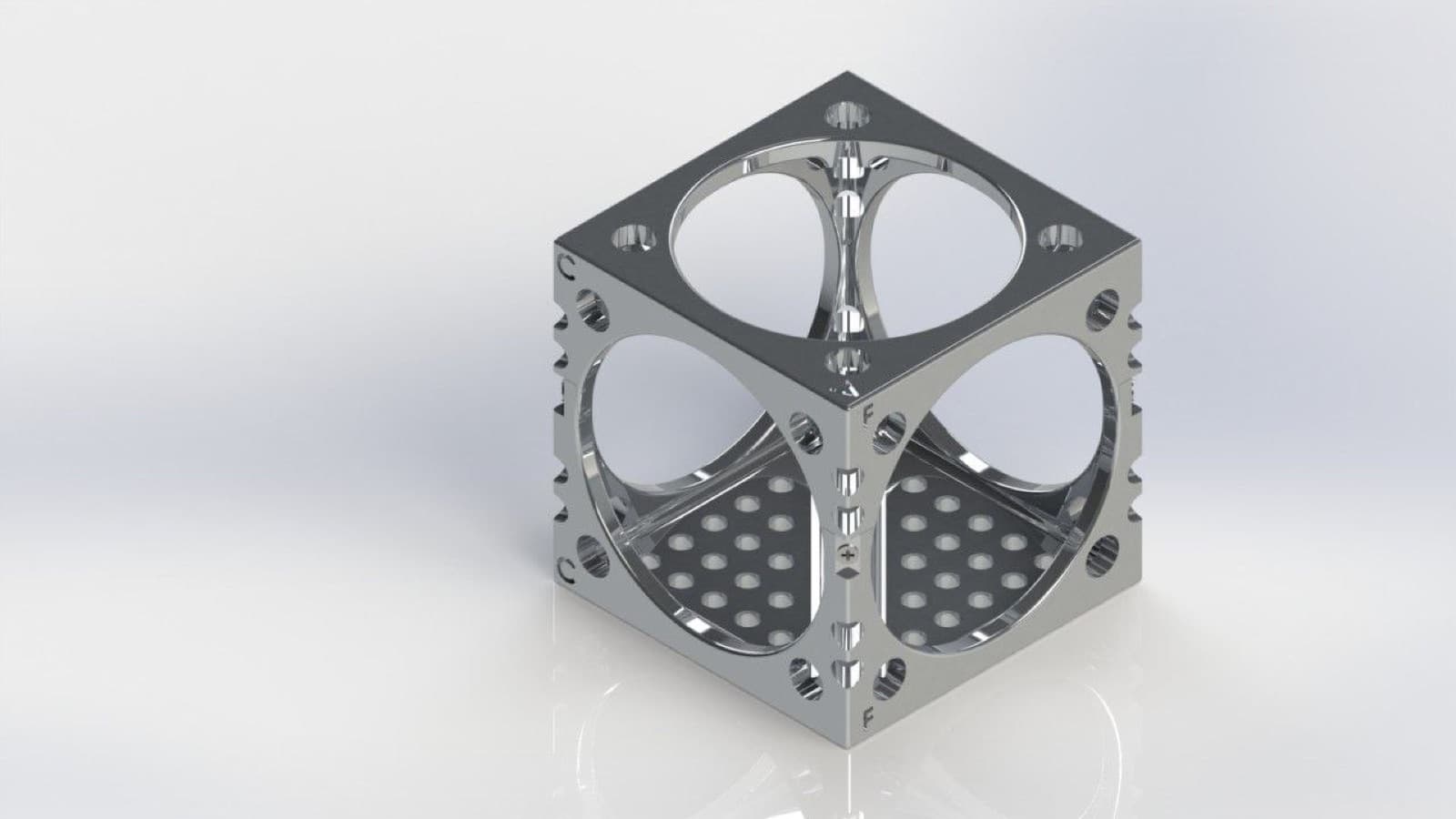 CAD model of a cube-shaped satellite frame: a circular aperture braced by cross ribs on each face, perforated internal panels and notched corner rails.