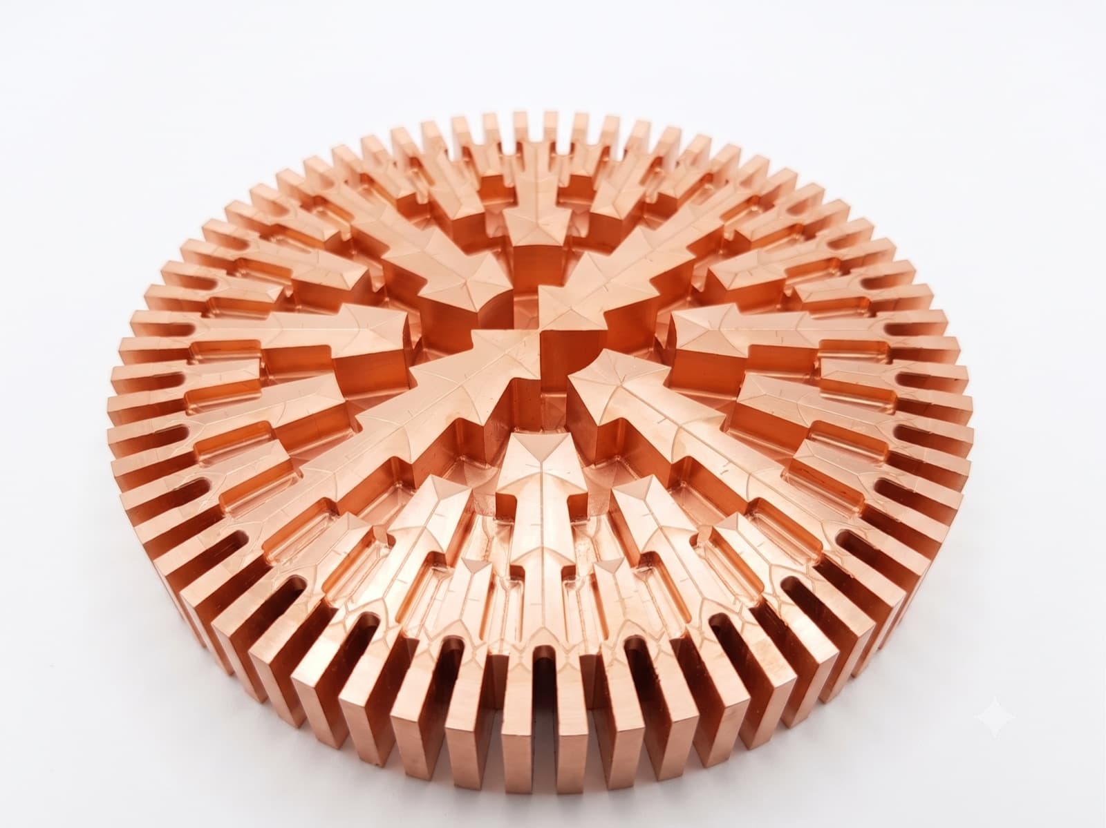 Machined copper part: a disc with a dense outer ring of radial fins and a radial vane structure around the centre.