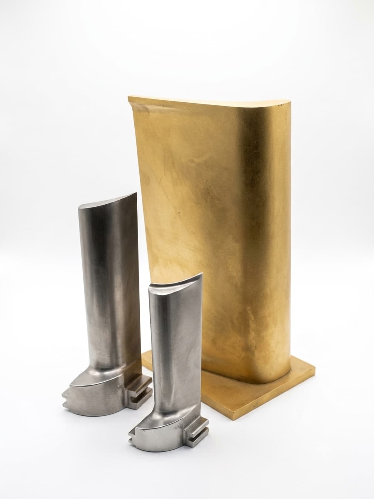 Three turbine blades of differing size and colour, with freeform aerofoil surfaces and machined root forms.